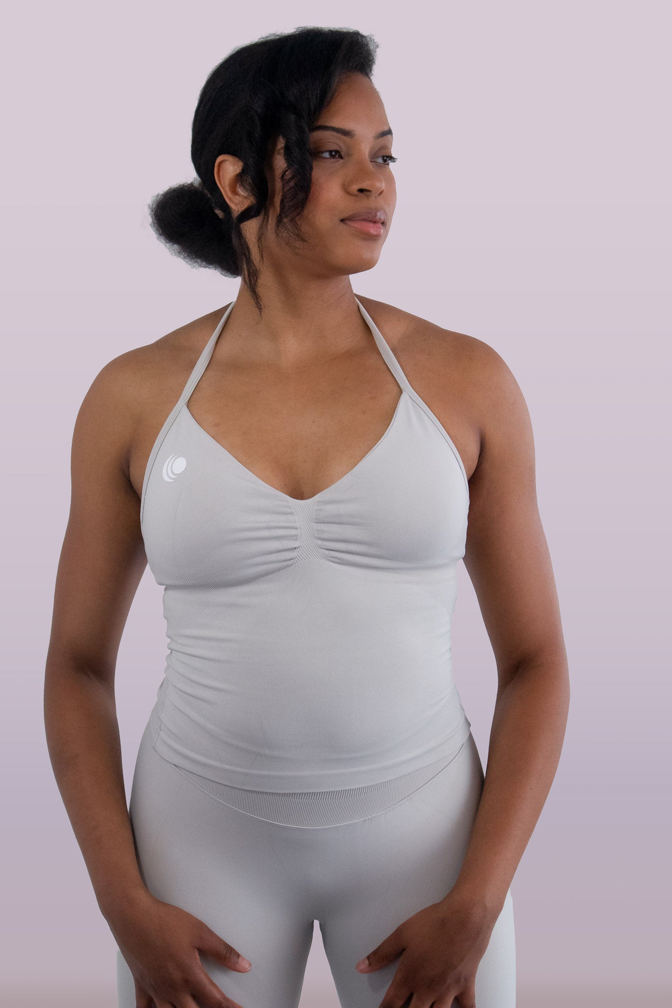 Woman wearing a light gray sports bra and leggings on a plain background